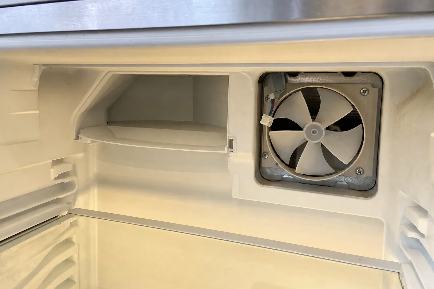 Circulation fan exposed behind an opening in the rear wall of an empty refrigerated compartment
